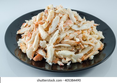 Crab meat, dish black, white background. Crab meat for cooking