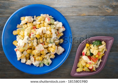 crab salad on dark blue  plate with vegetable salad top view. crab's salad on grey and blue wooden background
