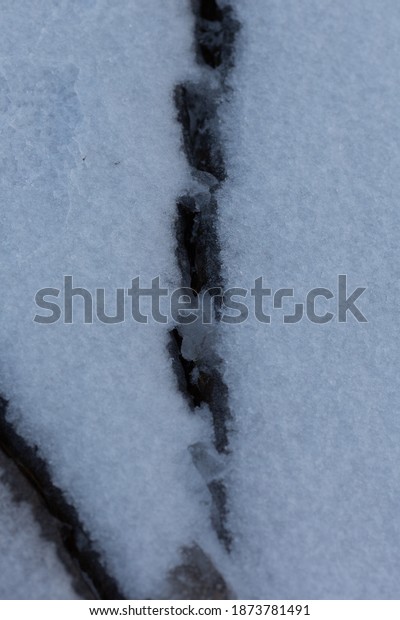 A crack in the ice under the snow. Dangerous ice\
with a crack.