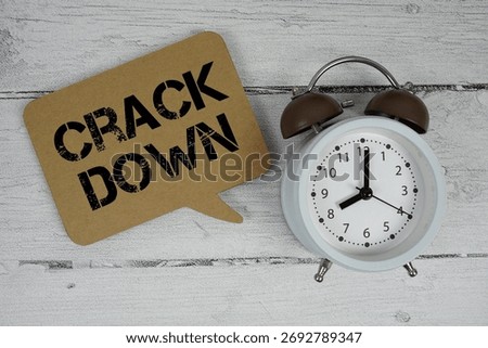 Crackdown text with alarm clock on wooden background