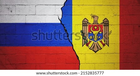 Cracked brick wall painted with a flag of Russia on the left and a flag of Moldova on the right.