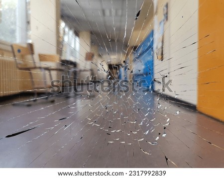 Cracked broken glass window in a school corridor. School violence. chairs and doors background