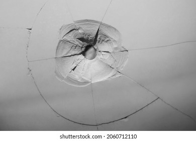 Cracked, broken porcelain wall tiles or panels - closeup view. bullet hole with cracks. 