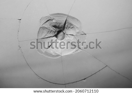 Cracked, broken porcelain wall tiles or panels - closeup view. bullet hole with cracks. 