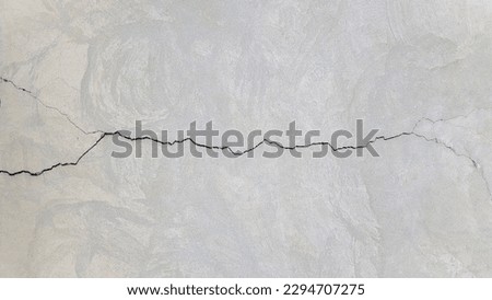 Cracked concrete surface covered with gray cement mortar. Destruction after the earthquake. Rough long winding crack in the wall. Copy space. Texture background. Repair, construction of buildings
