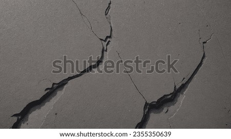 cracked concrete surface, taken from a low angle to emphasize the texture and depth of the cracks