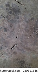 Cracked concrete surface texture represents a weathered, abstract pattern with deep fissures, suitable for grunge or industrial design backgrounds.