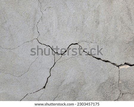 Cracked concrete wall covered with gray cement mortar. Destruction caused by an earthquake. Large uneven crack in the wall. Copy space. Texture background. Repair, construction of buildings, shrinkage