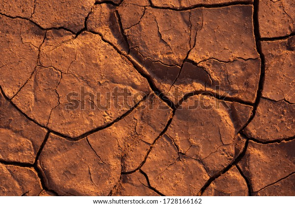 Cracked earth texture of ground, broken and rough\
surface red mud clay soil in summer season, crack ground floor on\
arid drought environment and hot weather in nature, light on top\
photo for graphic 