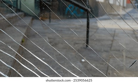 Cracked glass highlights urban decay and graffiti on a city street during daylight
 - Powered by Shutterstock