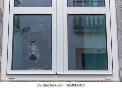 Cracked glass in a plastic vacuum window frame. A damaged window due to vandalism, natural disaster, or accident.