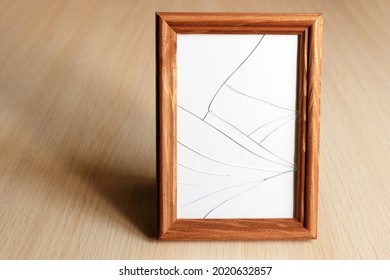 Cracked Glass. Wooden Frame For The Picture. Light Wood Surface.