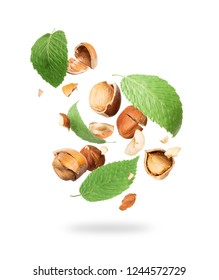 Cracked hazelnuts with leaves fall down on white background 