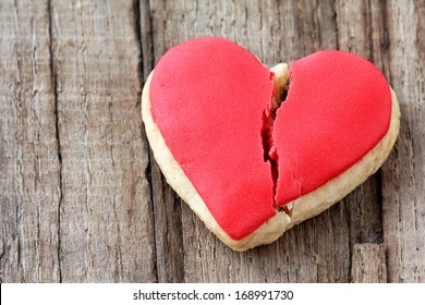 Cracked heart shaped cookie decorated with red icing as a concept of broken heart, breakup and end of relationship