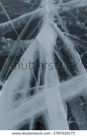 Cracked ice surface displays unique patterns and textures, featuring clear and frosty areas set against a dark, contrasting background