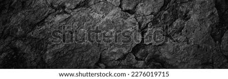 Cracked rock texture. Black white stone background. Grunge. Dark gray rough surface. Close-up. Broken, damaged, collapsed. Wide banner. Panoramic.	