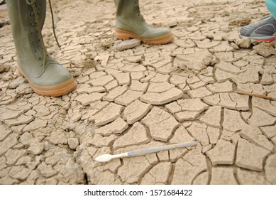 Cracked Soil Surface After Flood, Rubber Boots