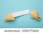 Cracked traditional fortune cookie with prediction on blue background