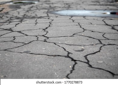 Cracked, Wet Asphalt Pavement. Traffic, Road Repairs, Weather And Poor Quality Concept. Urban Environment