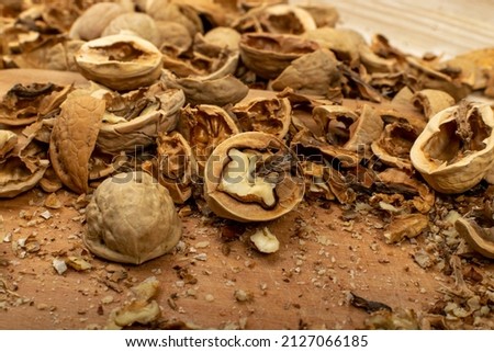 Cracking nuts on a wood table close up. Macro photo of crushed walnuts, broken walnut shells with kernel, nutshell heap, fresh raw healthy food