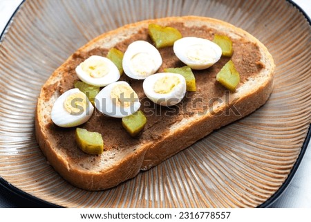 cracklings spread with pickled cucumber and boiled egg on slice of bread