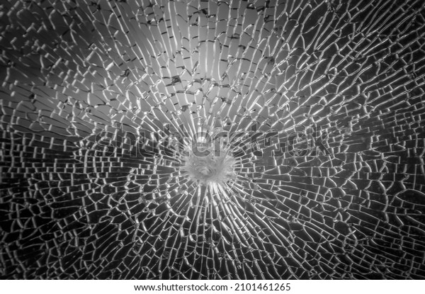 Cracks in the glass on the black
background or Bullet hole.  Cracked black concept. Abstract broken
glass texture on a black background on window car
transparent.