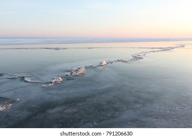 Cracks with ice crystals on frozen river at sunset, Ob reservoir, Siberia, Russia
