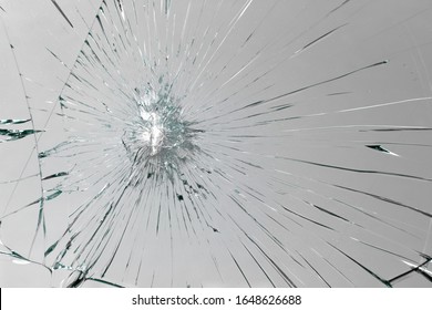 Cracks on broken glass from impact, white crack line fountain on window.
