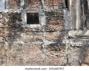 Cracks On The Red Brick Wall Of The Old Building Are Damaged. Wet With Moss And Dog Claw Marks On Shiny Leaf Walls