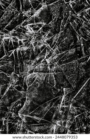 Cracks and scratches create the effect of broken glass or ice on a black background. Distressed texture.