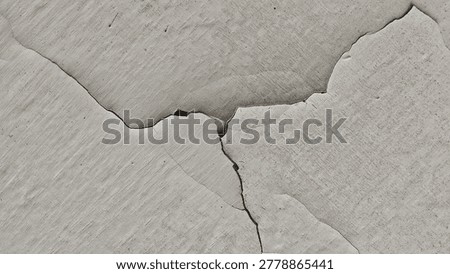 Cracks split weathered plaster surface. Texture shows age and wear. Gray tones imply decay or neglect.