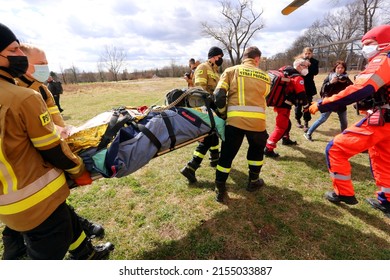 Cracow, Malopolska, Poland - 04.08.2022: Paramedics and firefighters loading patient onto an air rescue helicopter during the training exercise of simulated mass casualties accident.