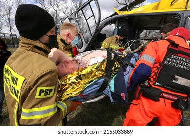 Cracow, Malopolska, Poland - 04.08.2022: Paramedics and firefighters loading patient onto an air rescue helicopter during the training exercise of simulated mass casualties accident.