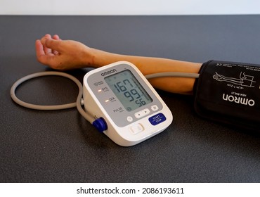 Cracow, Poland - December 2021: A blood pressure apparatus showing too high both systolic diastolic value of human blood pressure and an arm during measuring it. Selected focus.