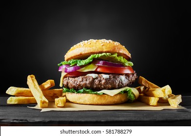 Craft beef burger and french fries on wooden table isolated on black background. - Shutterstock ID 581788279