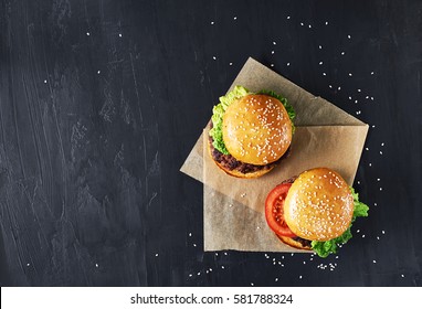 Craft beef burgers with vegetables. Flat lay on black textured background with sesame seeds. - Powered by Shutterstock