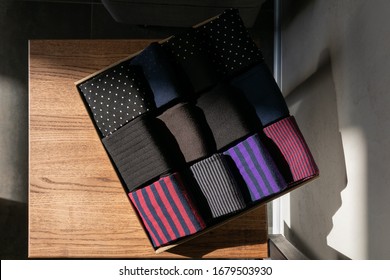 Craft cardboard box with a set of colorful men's socks on wooden surfaces under a sunlight