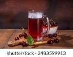 Craft cherry beer or cider alcohol drink mug and bottle on wooden table with fresh ripe cherries, copy space