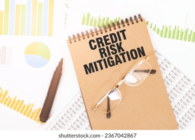 In a craft colour notebook is a CREDIT RISK MITIGATION inscription, next to pencils, glasses, graphs and diagrams. - Powered by Shutterstock