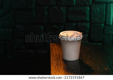 Craft cup with coffee on a wooden table against a brick wall. Coffee mock up template. Place for text
