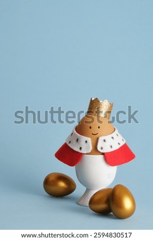 A craft Easter egg of a king with a crown and red robe on a blue background. Idea for children's creativity.