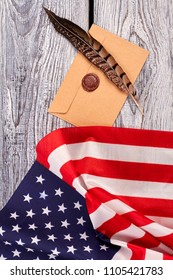 Craft envelope with stamp and American flag. Top view on brown feather, envelope and USA flag, vertical image.