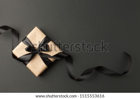 Craft gift box on a dark background, decorated with a textured bow and feathers, creating a romantic luxury atmosphere. For birthday, anniversary presents, gift post cards.