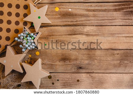 Craft gift boxes in the star shape with beads and confetti on a wooden table. New Year Flat lay with space for text