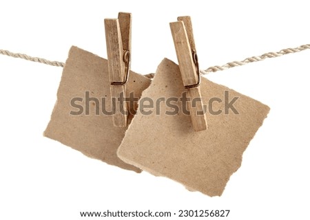 Craft note paper pinned with an old wooden clothespin on a rope on a white background. Place for text