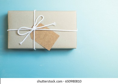 Craft Paper Wrapped Gift With Brown Craft Paper Card Tag On Blue Canvas Background