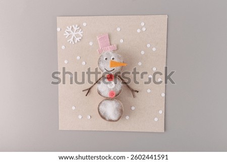A craft project featuring a snowman made from various materials on brown paper. Perfect for craft businesses, DIY stores, or seasonal decoration suppliers. 