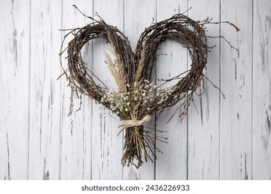 Crafted Wicker heart shaped wreath of birch branches hanging on white aged wooden background. Handmade DIY decoration - Powered by Shutterstock