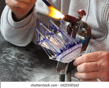 Craftman Or Glassworker Creating A Three-masted Sailing Ship From Glass And Fire. Artwork, Part Of A Serie.