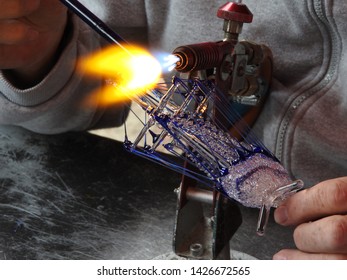 Craftman Or Glassworker Creating  A Three-masted Sailing Ship From Glass. Flames. Artwork, Part Of A Serie.